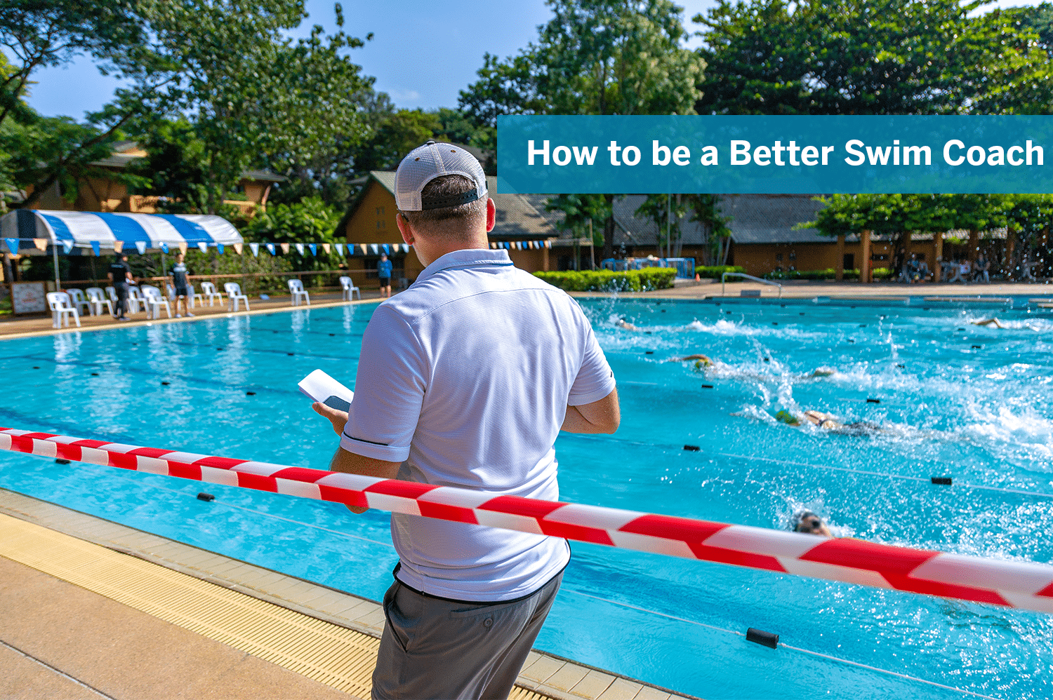 A swim coach watching his swimmers race in an outdoor pool.